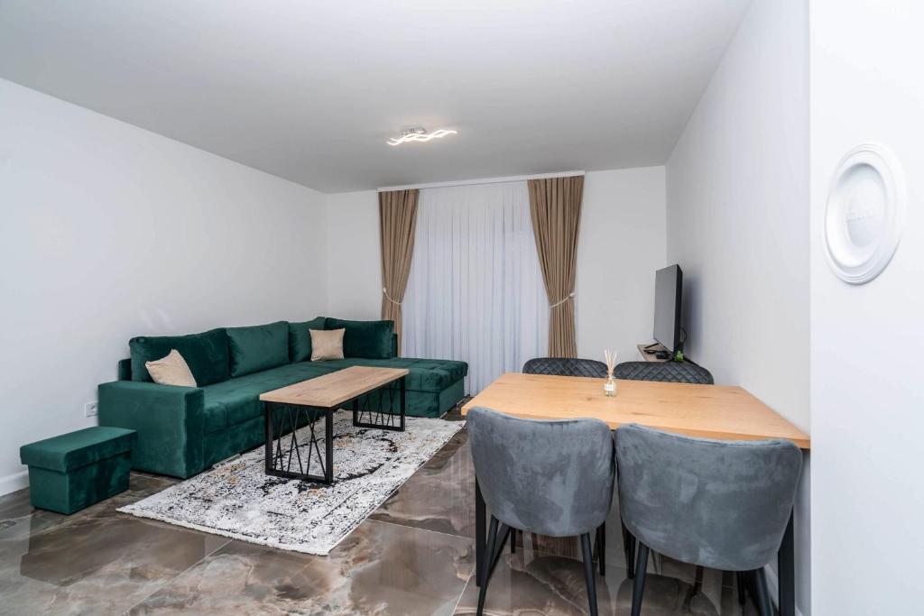 Dnevni boravak apartmana od 45 m² sa zelenom ugaonom garniturom i trpezarijom