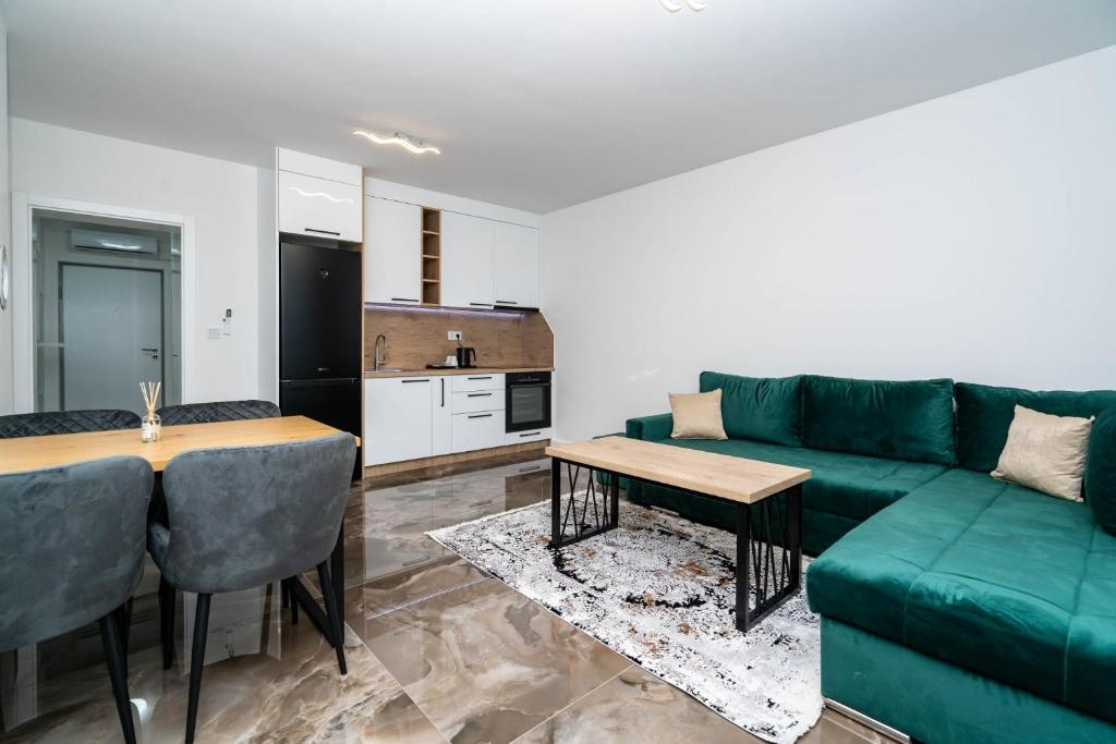 Dnevni boravak apartmana sa zelenom ugaonom garniturom i otvorenom kuhinjom